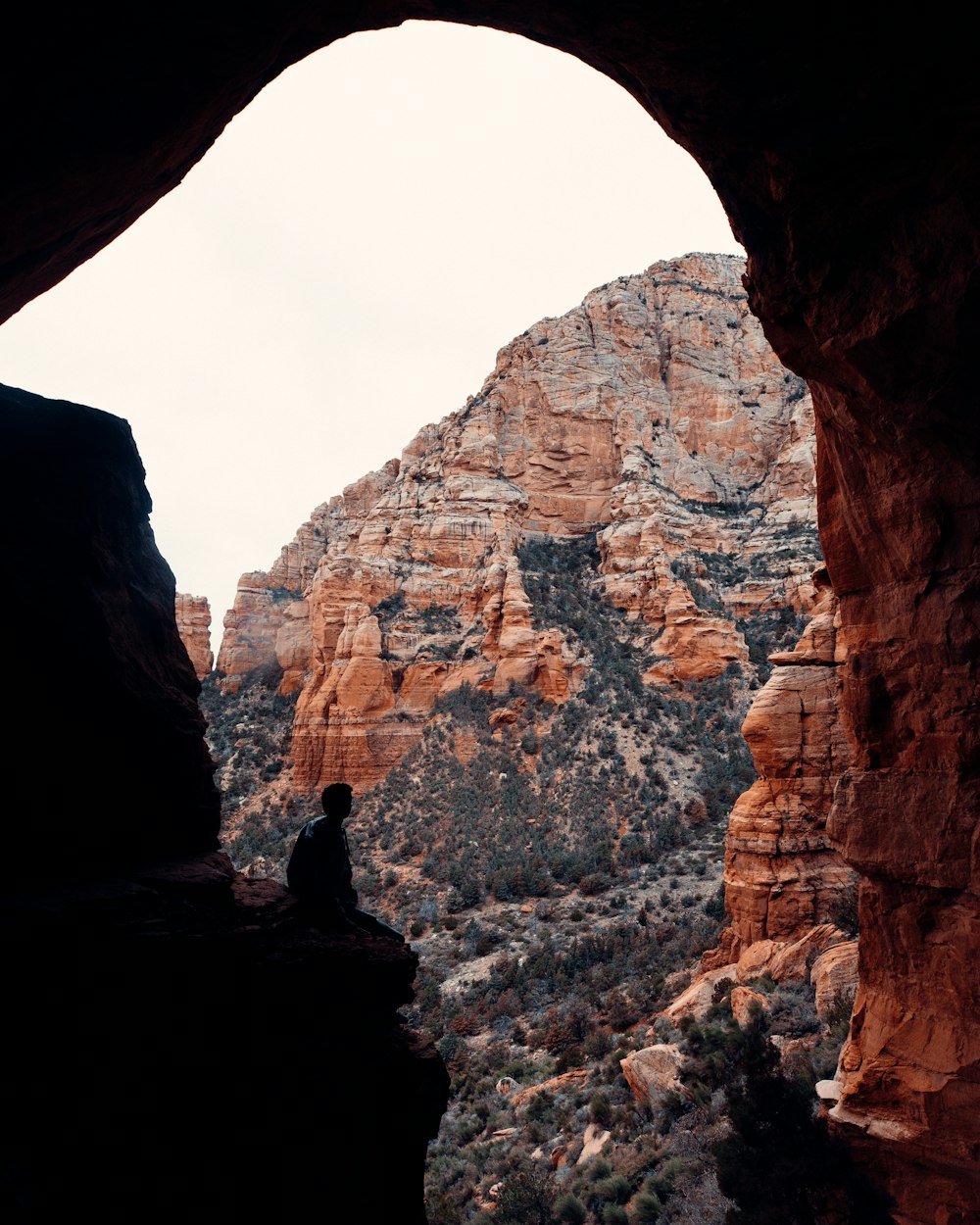 silhouette of person standing on rock formation during daytime