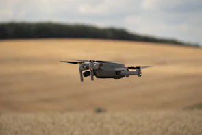 Autonomous drone inspecting a vast agricultural field under clear blue skies.