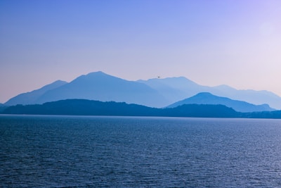 body of water near mountain during daytime