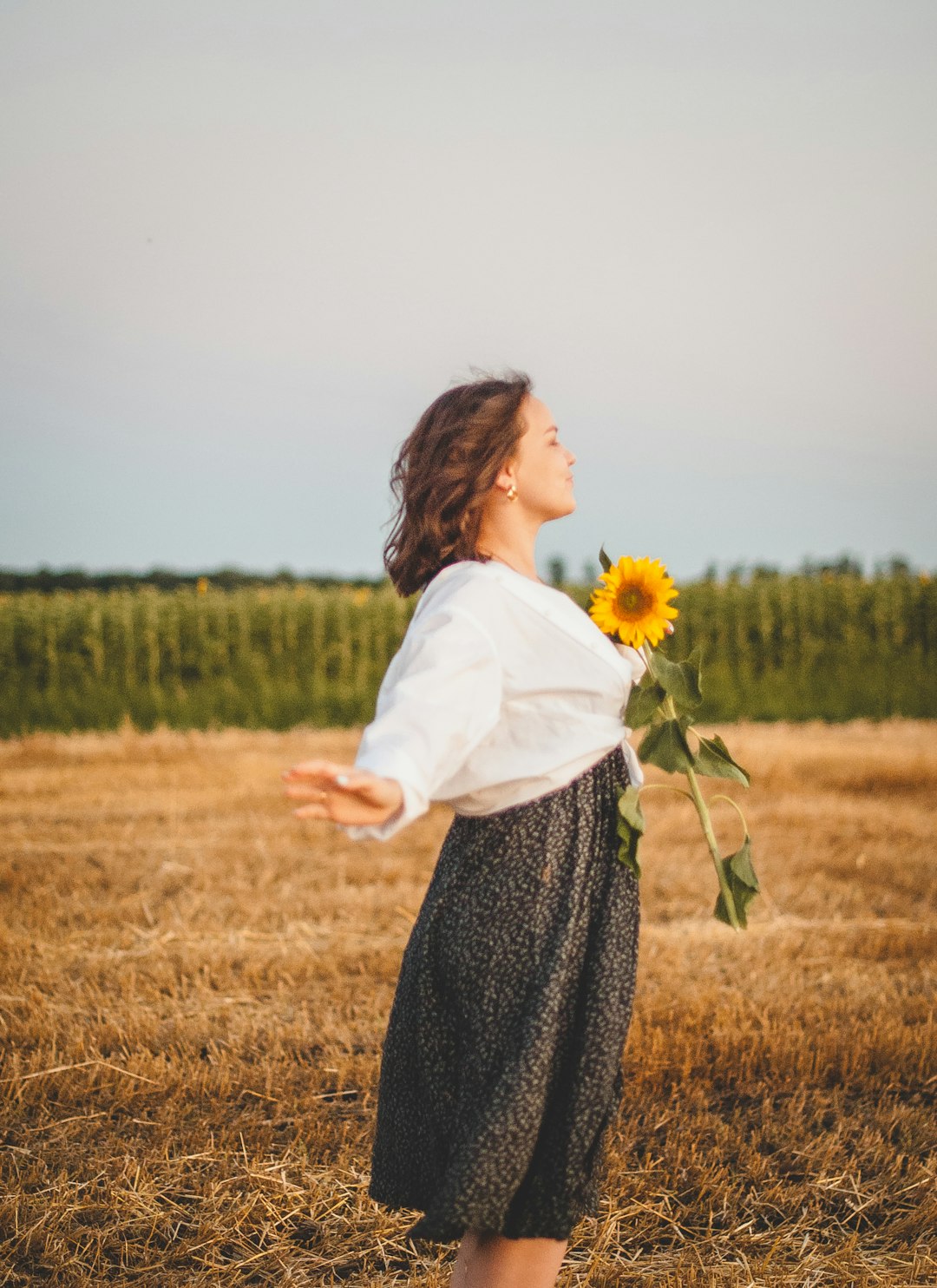 woman in white long sleeve shirt and black skirt standing on brown grass field during daytime