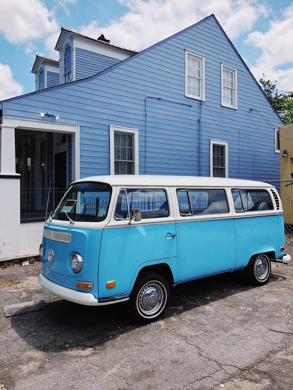 blue and white volkswagen t-2 parked beside white and blue wooden house during daytime