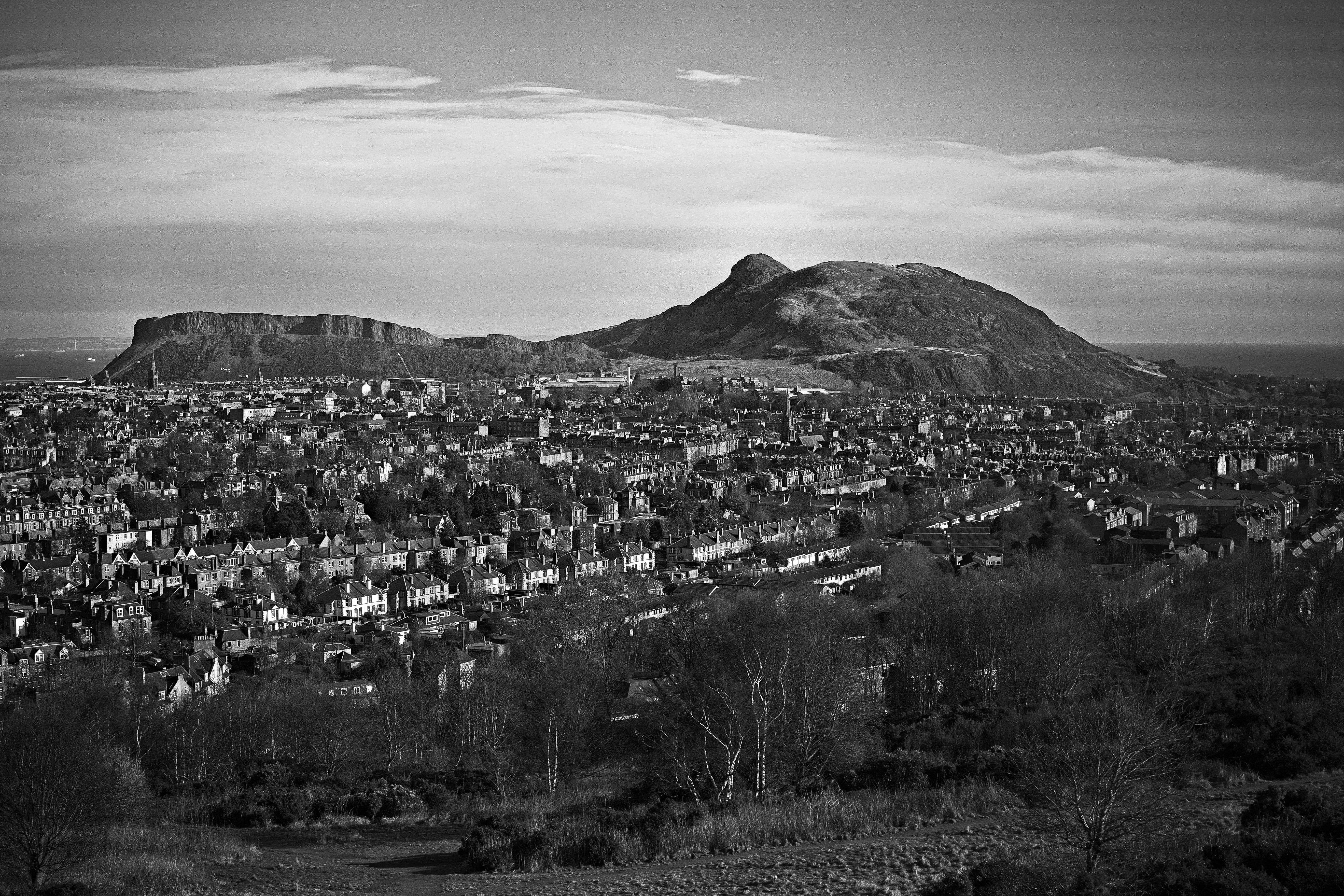 city buildings near mountain under cloudy sky during daytime