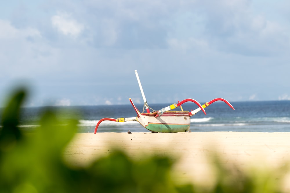 red and green boat on brown sand during daytime