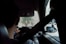 A person is driving a car with a seatbelt fastened. The view is from the back seat, showing their hands on the steering wheel. Outside the front windshield, two motorcyclists are visible on a blurry road.