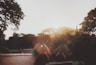 person in black jacket sitting on brown wooden bench during sunset