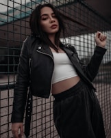 woman in black leather jacket standing beside black metal fence