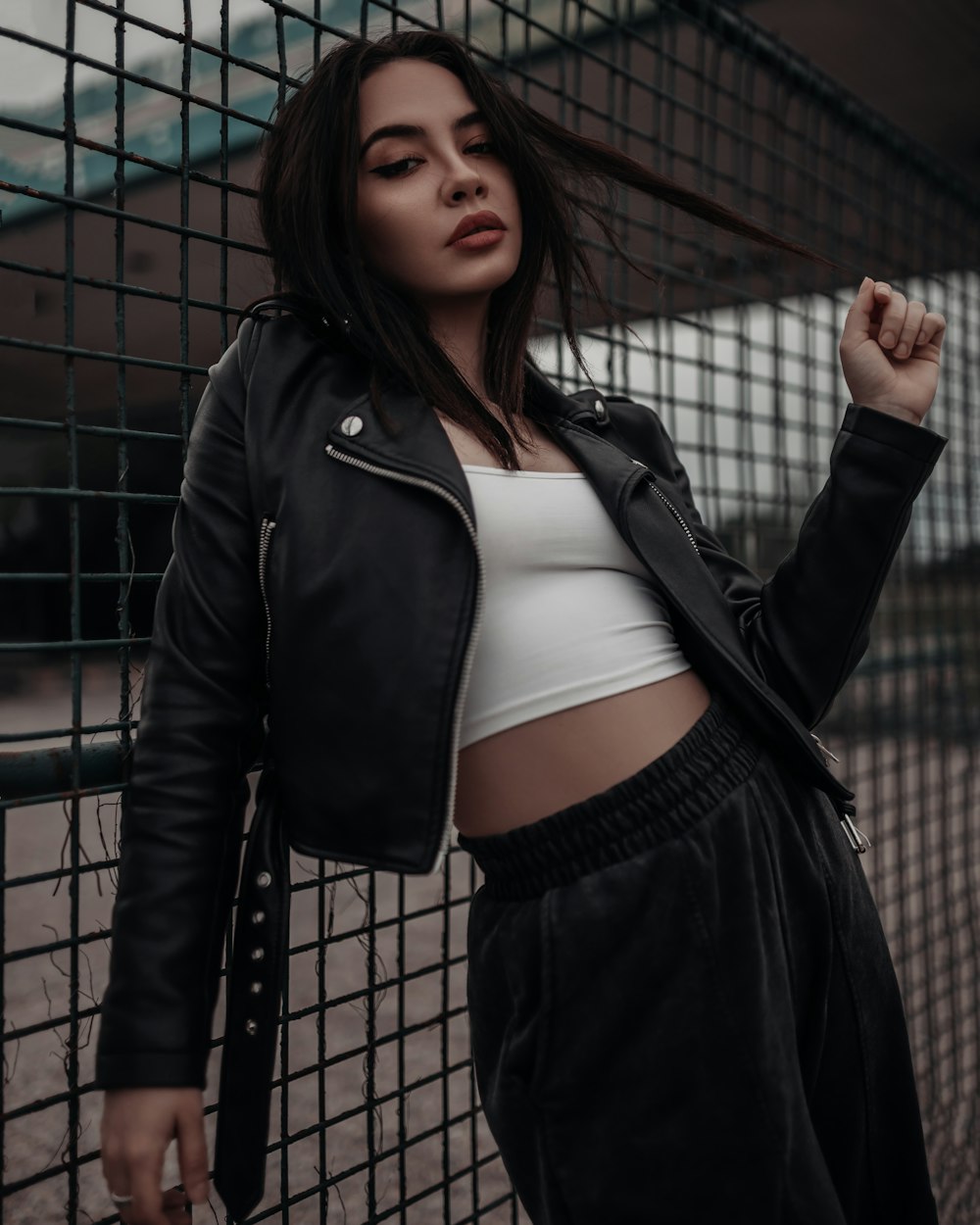 Donna in giacca di pelle nera in piedi accanto alla recinzione metallica nera