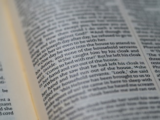A close-up view of a page from a book, with text printed in two columns. The text is in English and is clearly visible, with some words highlighted through natural focus effects.