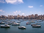 white and blue boats on sea near city buildings under blue sky during daytime