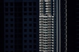 High-rise residential buildings are depicted with shadow-covered facades, highlighting vertical lines and geometric patterns in an urban setting.