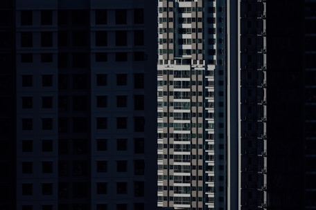 High-rise residential buildings are depicted with shadow-covered facades, highlighting vertical lines and geometric patterns in an urban setting.