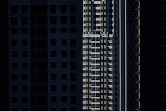 High-rise residential buildings are depicted with shadow-covered facades, highlighting vertical lines and geometric patterns in an urban setting.