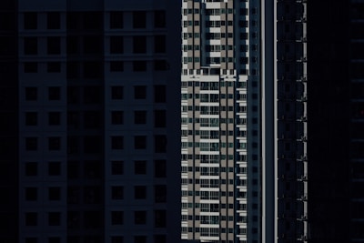 High-rise residential buildings are depicted with shadow-covered facades, highlighting vertical lines and geometric patterns in an urban setting.