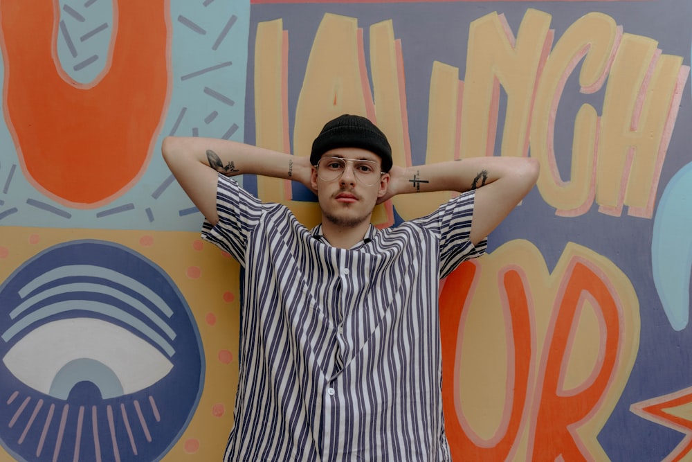 man in black and white striped button up shirt standing beside wall with graffiti