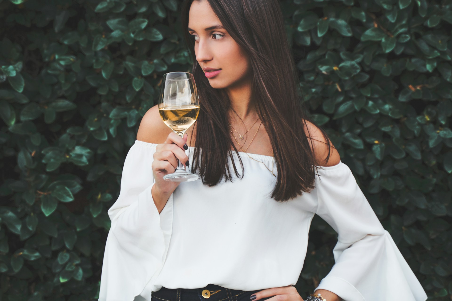 woman in white long sleeve shirt holding clear drinking glass