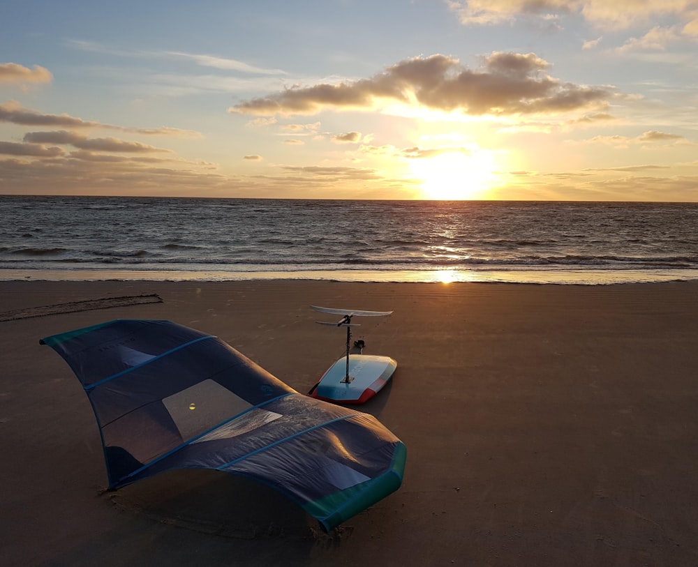 blue and white boat on beach during sunset