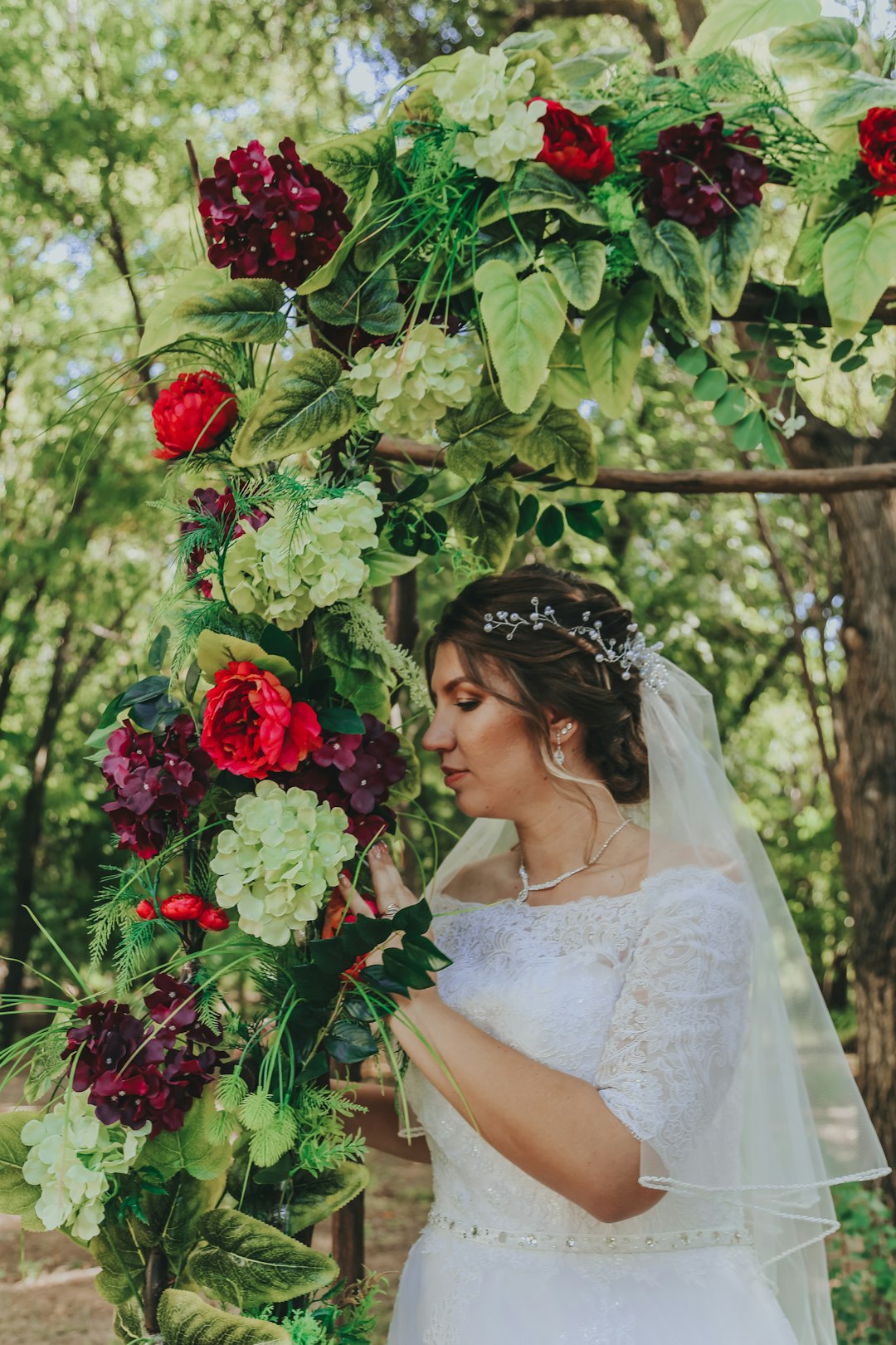 woman in white wedding dress holding red rose bouquet