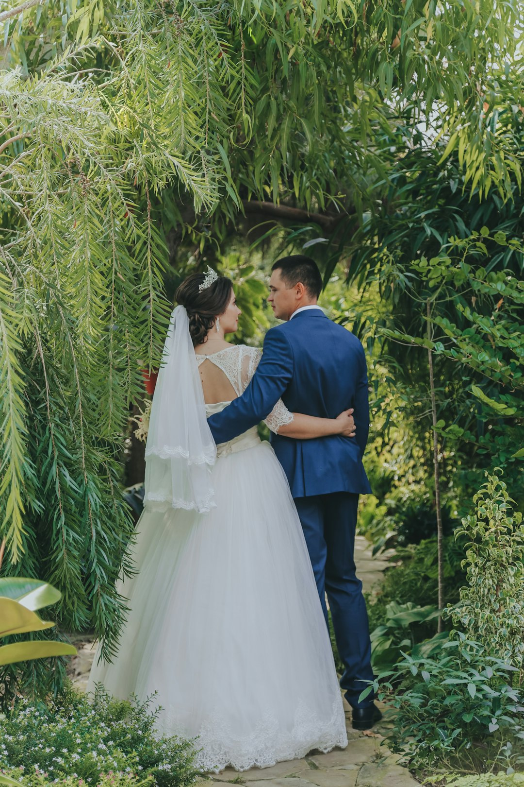 man in blue suit and woman in white wedding dress kissing