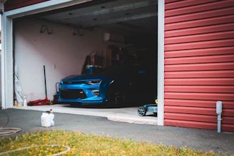 blue car parked beside red garage door