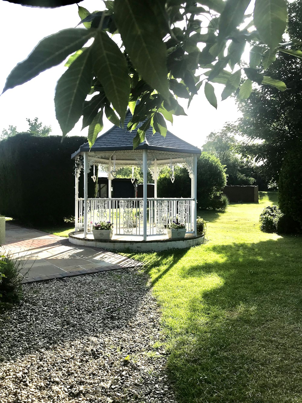 white wooden gazebo near green trees during daytime