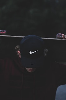 A stylish cap resting on a skateboard, with city buildings blurred in the background.