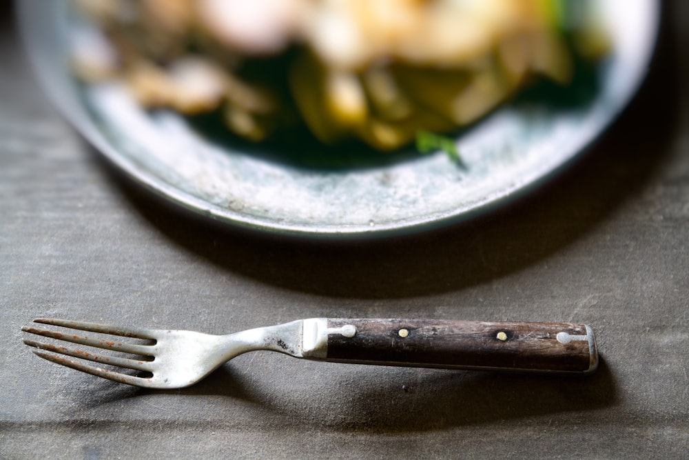 stainless steel fork beside black round plate