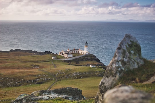 white and brown concrete building on green grass field near body of water during daytime in Neist Point Lighthouse United Kingdom