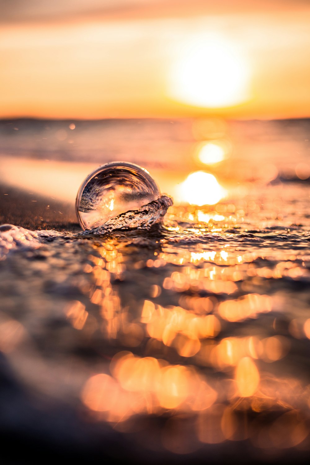 sfera di vetro trasparente sulla spiaggia durante il tramonto