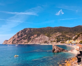 people riding on boat on sea near mountain under blue sky during daytime