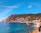 people riding on boat on sea near mountain under blue sky during daytime