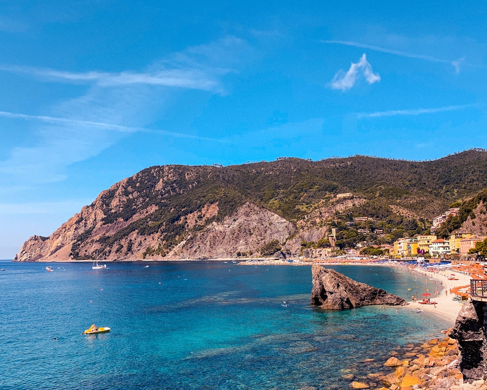 persone che cavalcano in barca sul mare vicino alla montagna sotto il cielo blu durante il giorno