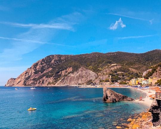 people riding on boat on sea near mountain under blue sky during daytime in Parco Nazionale delle Cinque Terre Italy