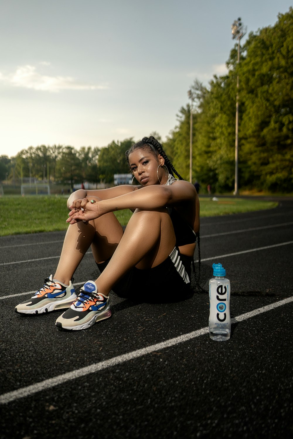 woman in black tank top and black shorts sitting on gray concrete road during daytime