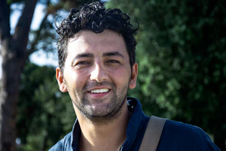 Close-up of a confident man with thick, healthy hair smiling outdoors