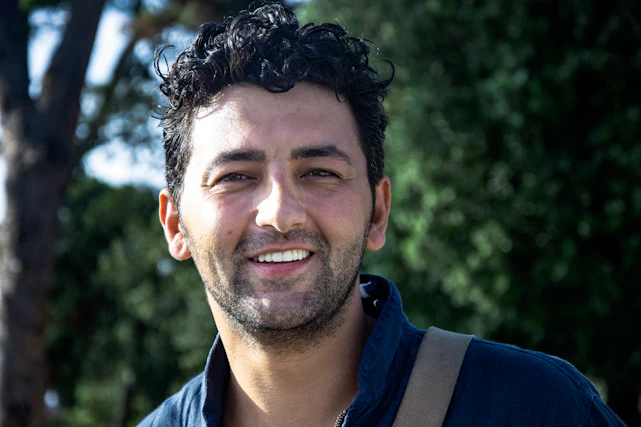 Close-up of a confident man with thick, healthy hair smiling outdoors
