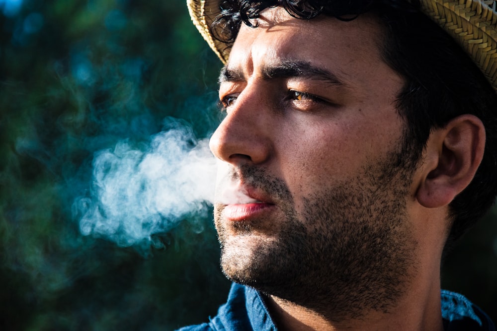 man in blue shirt with white smoke in his face
