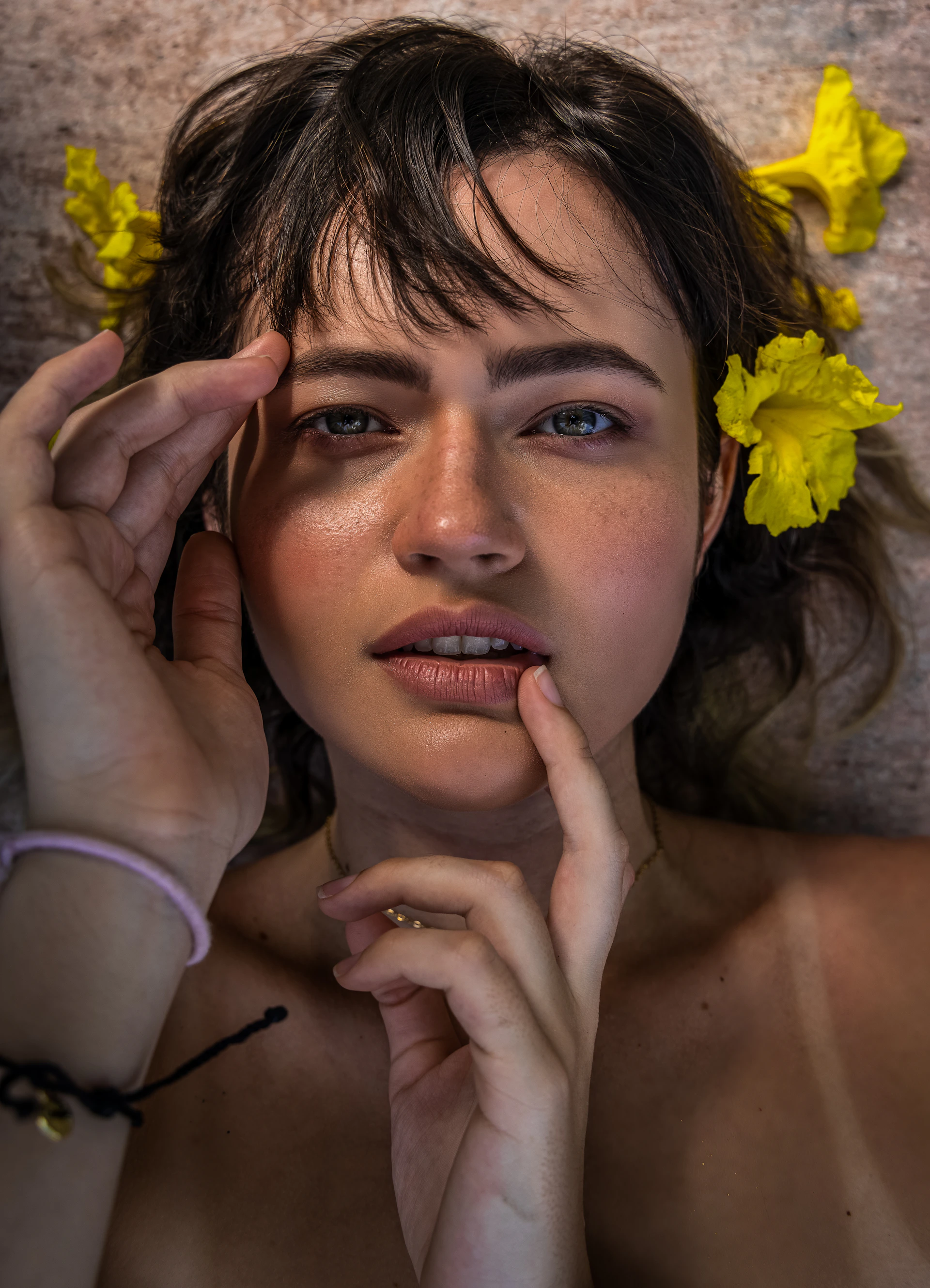 woman in gray tank top holding yellow flower