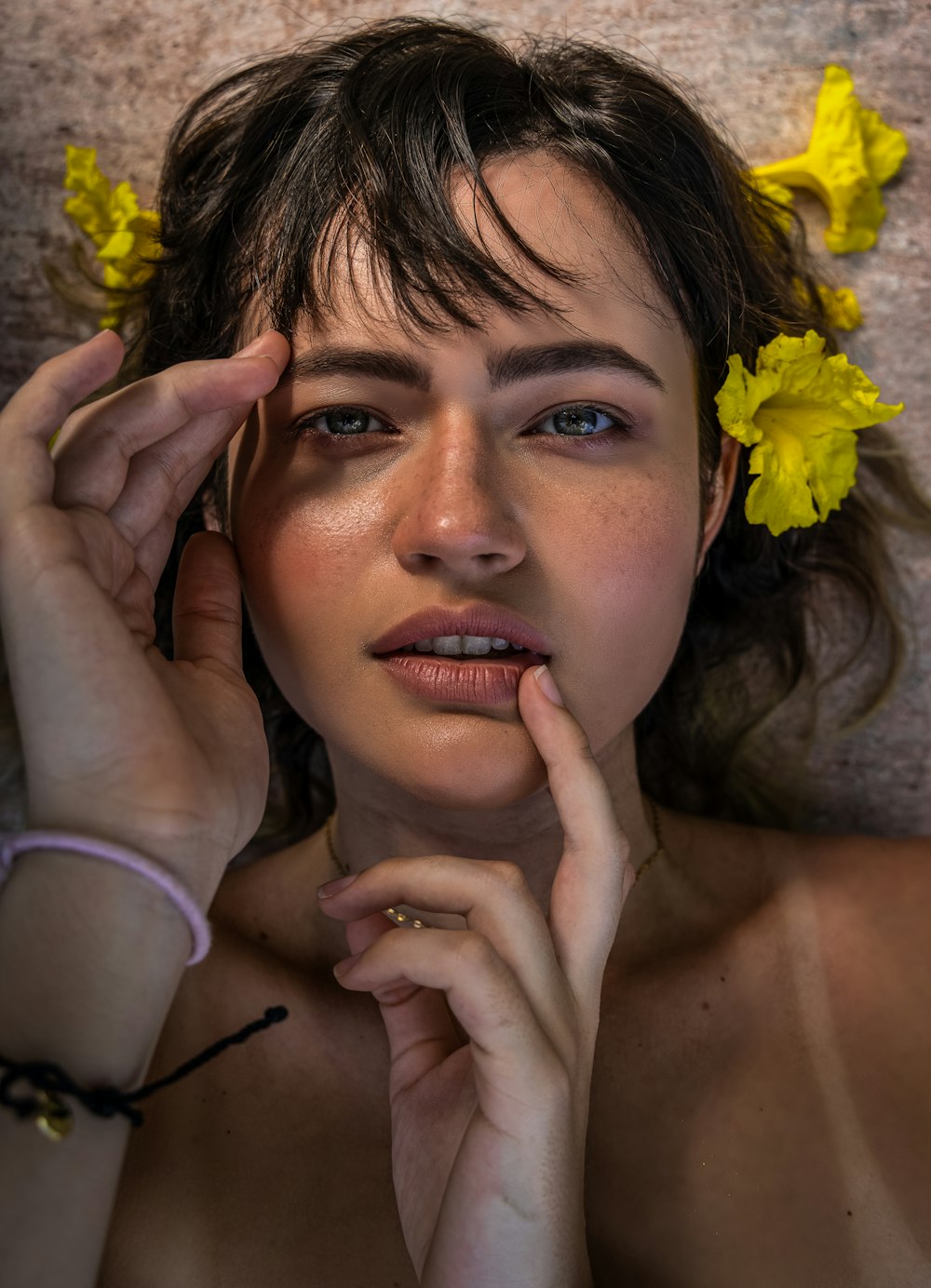 woman in gray tank top holding yellow flower