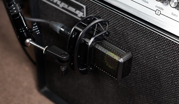 Close-up of a sleek lavalier microphone clipped to a guitar amplifier.