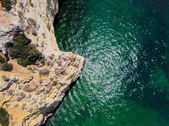 brown rocky mountain beside body of water during daytime in Portimão Portugal