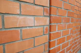 Close-up of bricklayer carefully placing bricks on a wall under bright daylight.