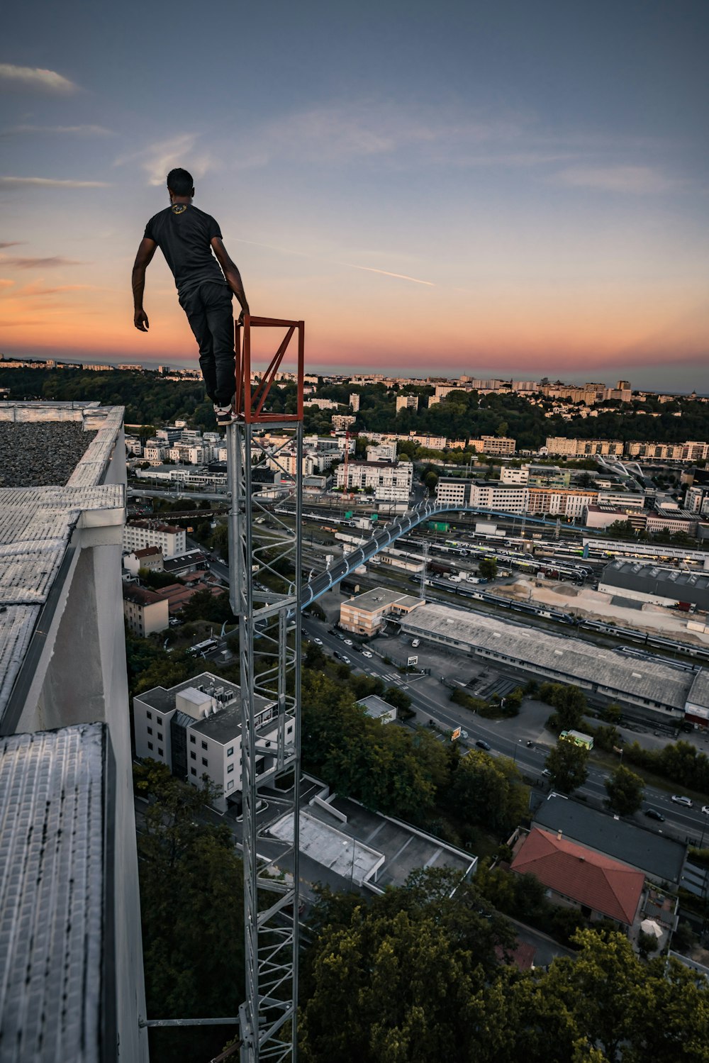 man in black jacket and pants standing on top of building during sunset