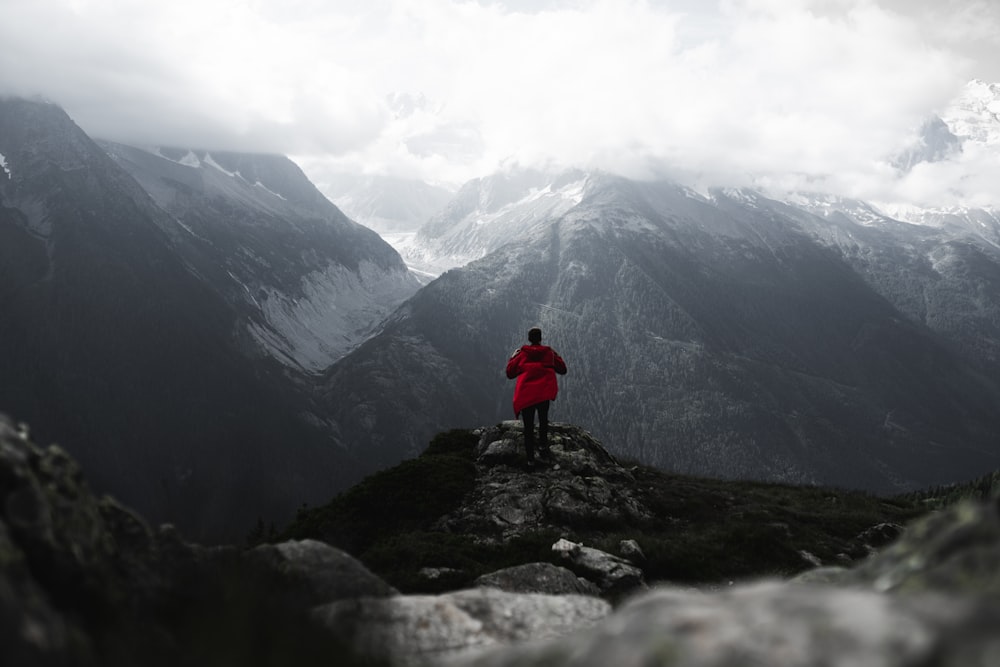 person in red jacket standing on rock mountain during daytime