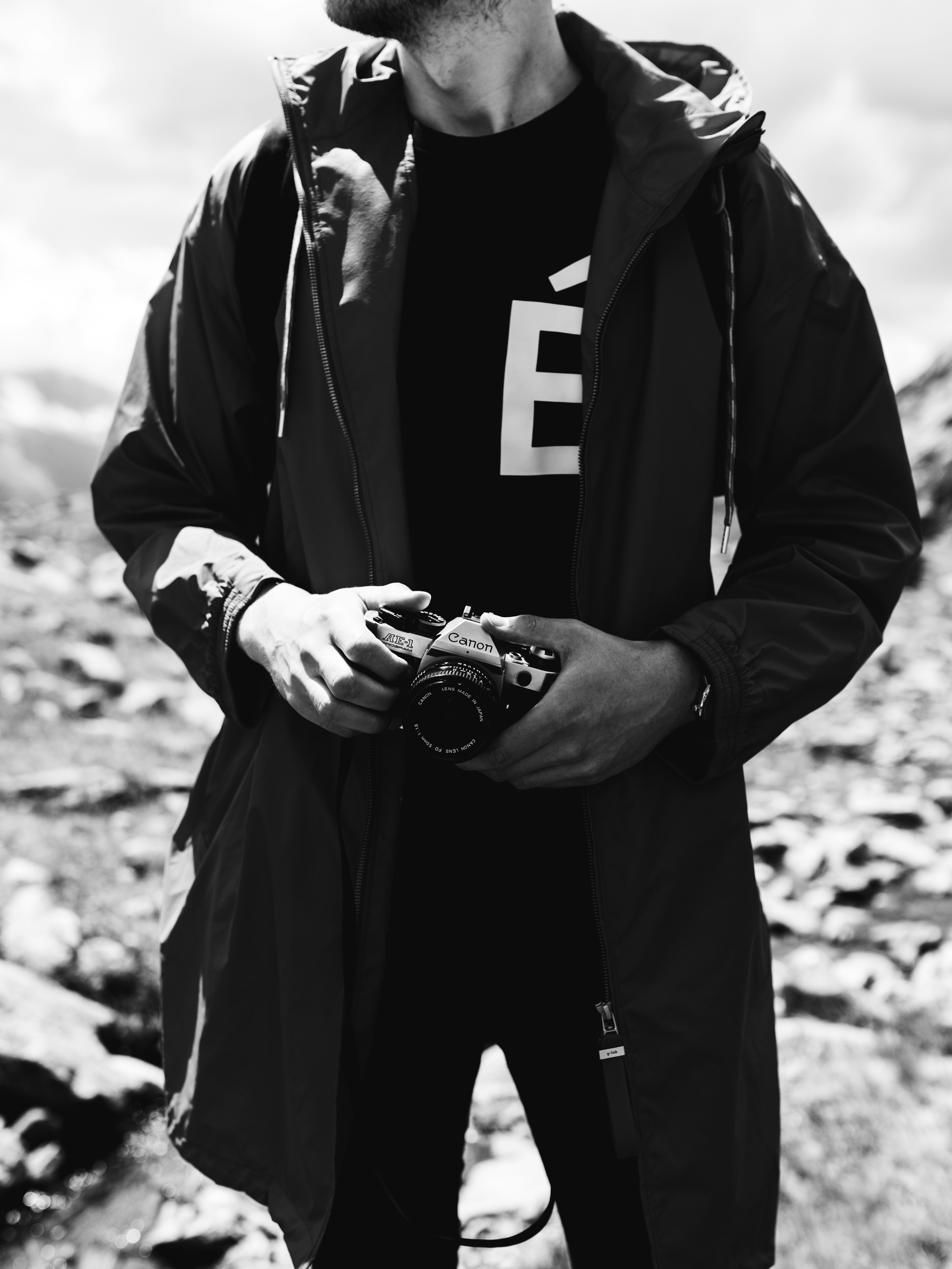 Man in black zip up jacket holding black and silver dslr camera photo