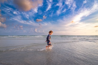 girl in black and white plaid dress shirt and black shorts running on siesta beach during daytime