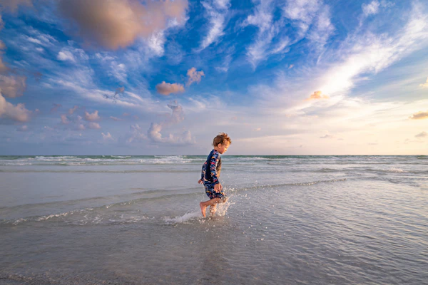 girl in black and white plaid dress shirt and black shorts running on siesta beach during daytime