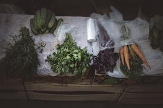 Fresh vegetables and herbs arranged on a wooden table.