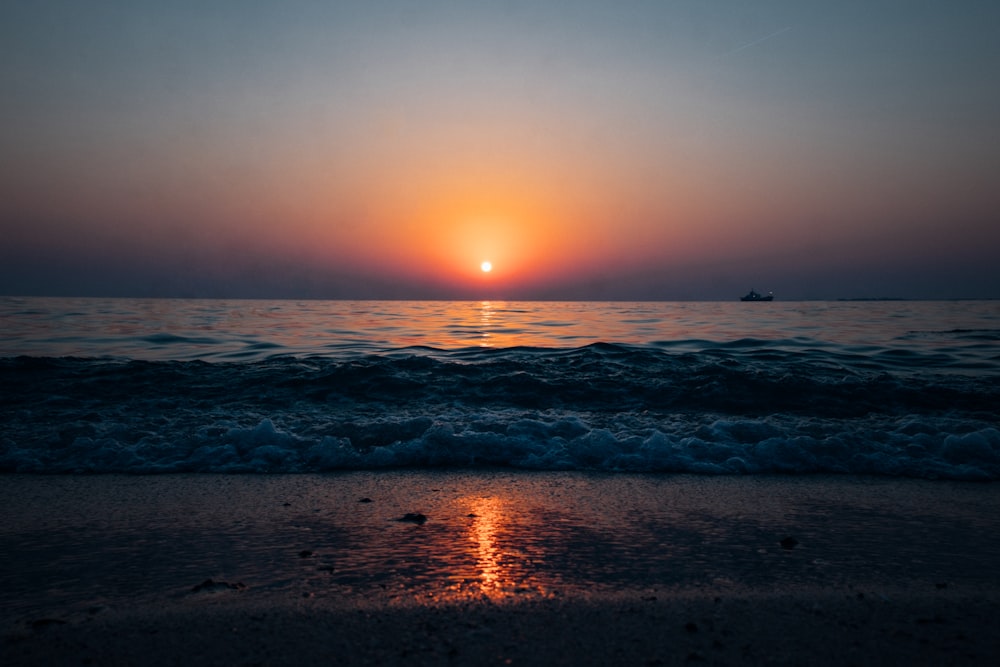 ocean waves crashing on shore during sunset