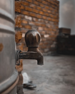 A close-up of a shiny PVC water tap with a backdrop of shipping containers ready for export.