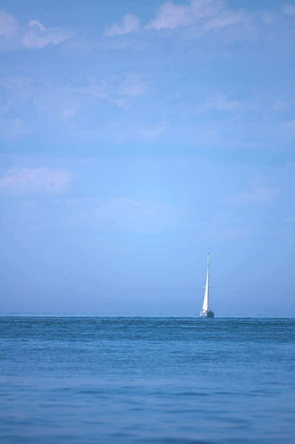 white sailboat on sea under blue sky during daytime